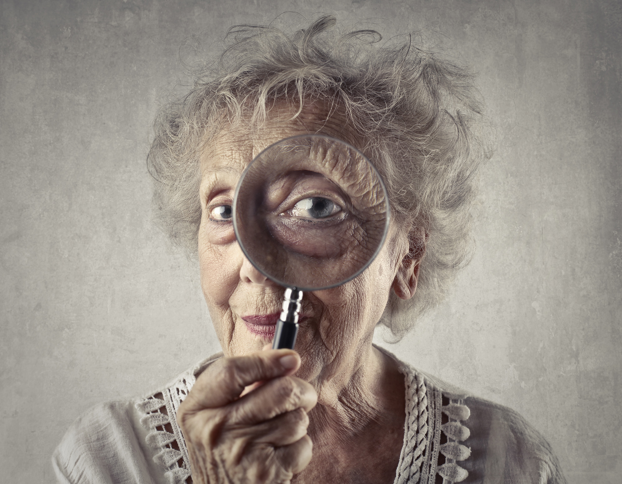 Elderly woman looking through a magnifying glass