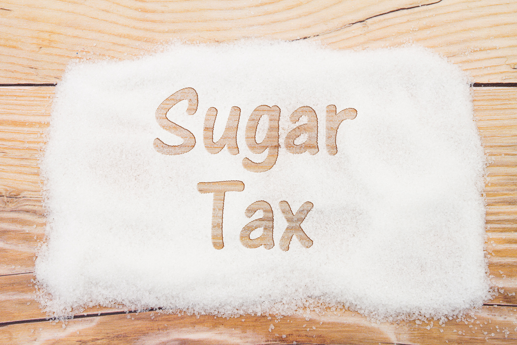 Close-up of sugar with text Sales Tax on weathered wood backgrou