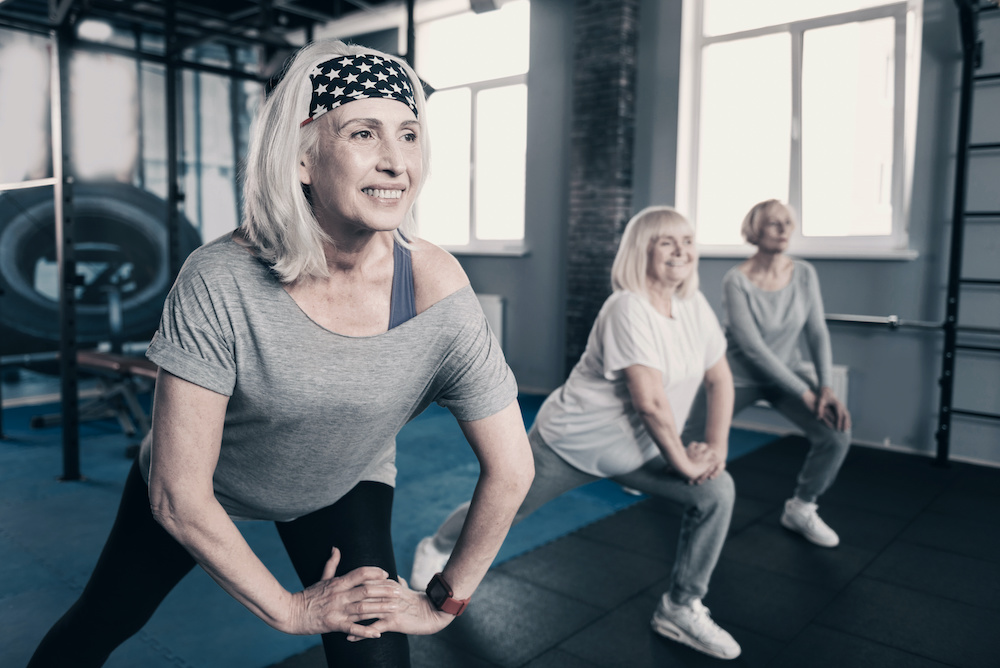 Three elderly women doing lunges in gym