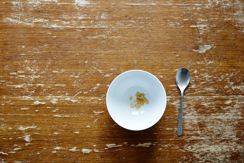 empty bowl with little cereal on dark wooden table