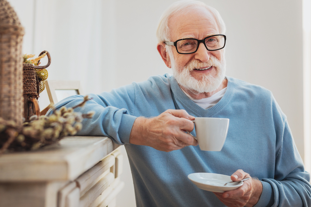 Smart elderly man drinking coffee while having break